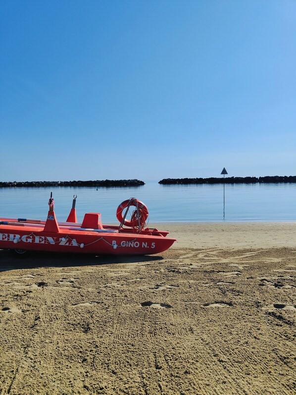 A red lifeboat named "ERGENZA" with the number "B. GINO N. 5" on a sandy beach.