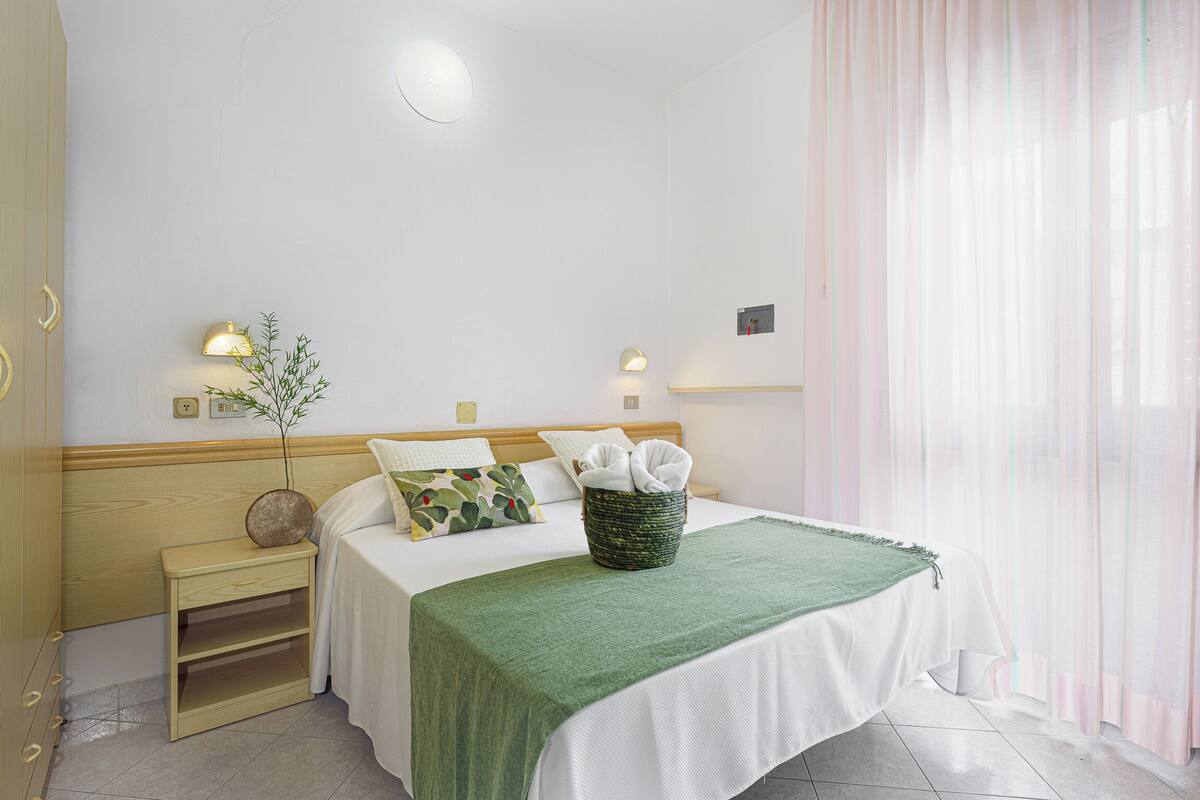 Un dormitorio ordenado con cama, mesitas de noche y una lámpara de pared.