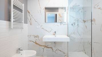 A modern bathroom with a white sink, a mirror, and a glass shower enclosure.
