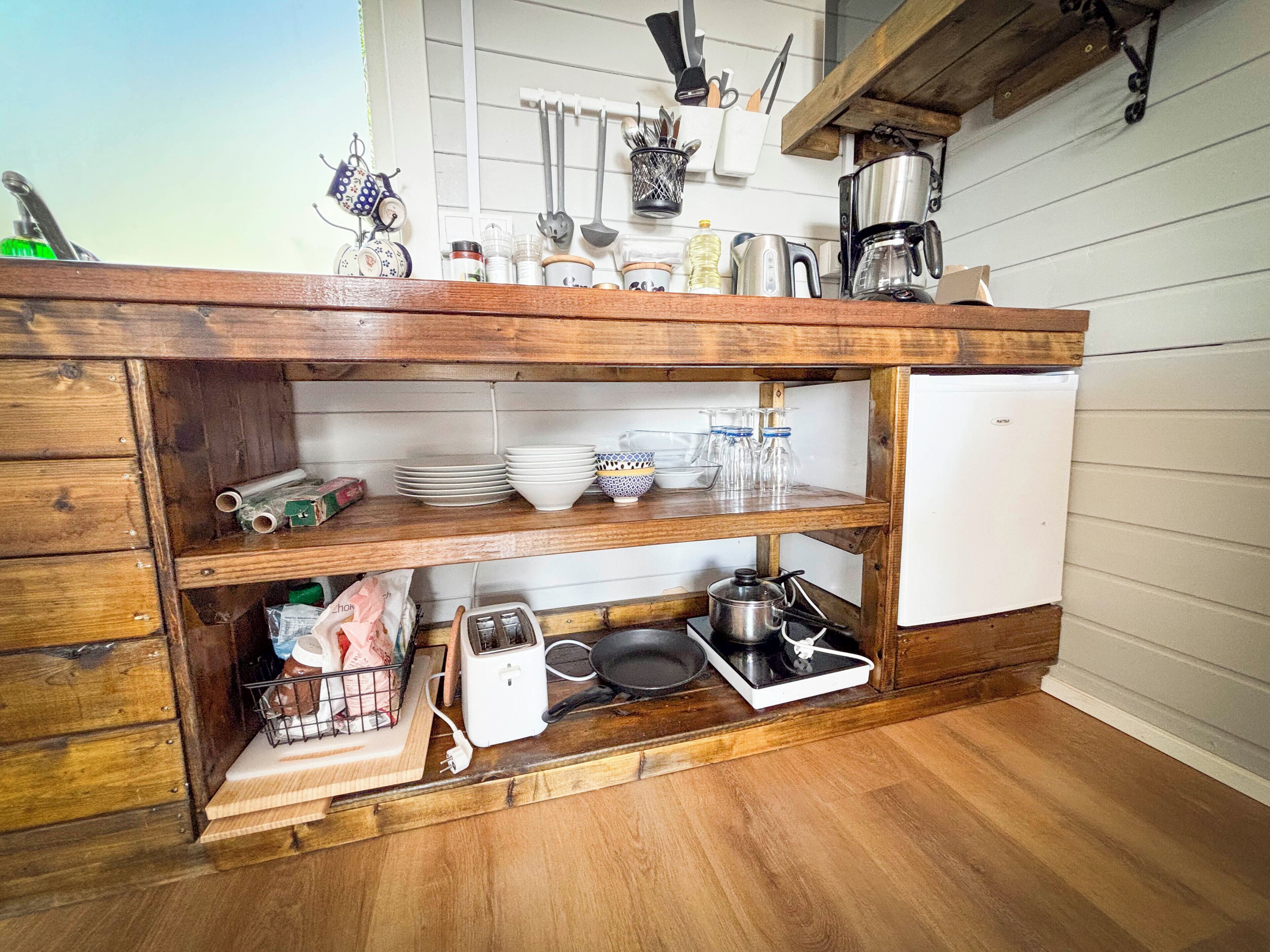 A kitchen with wooden cabinetry, a white refrigerator, and various kitchen utensils and appliances.
