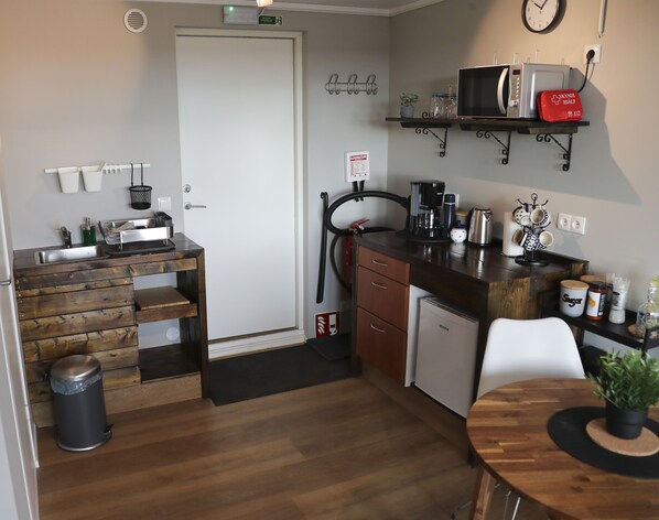 A compact kitchen with a wooden countertop, a coffee maker, a microwave, and a small refrigerator.