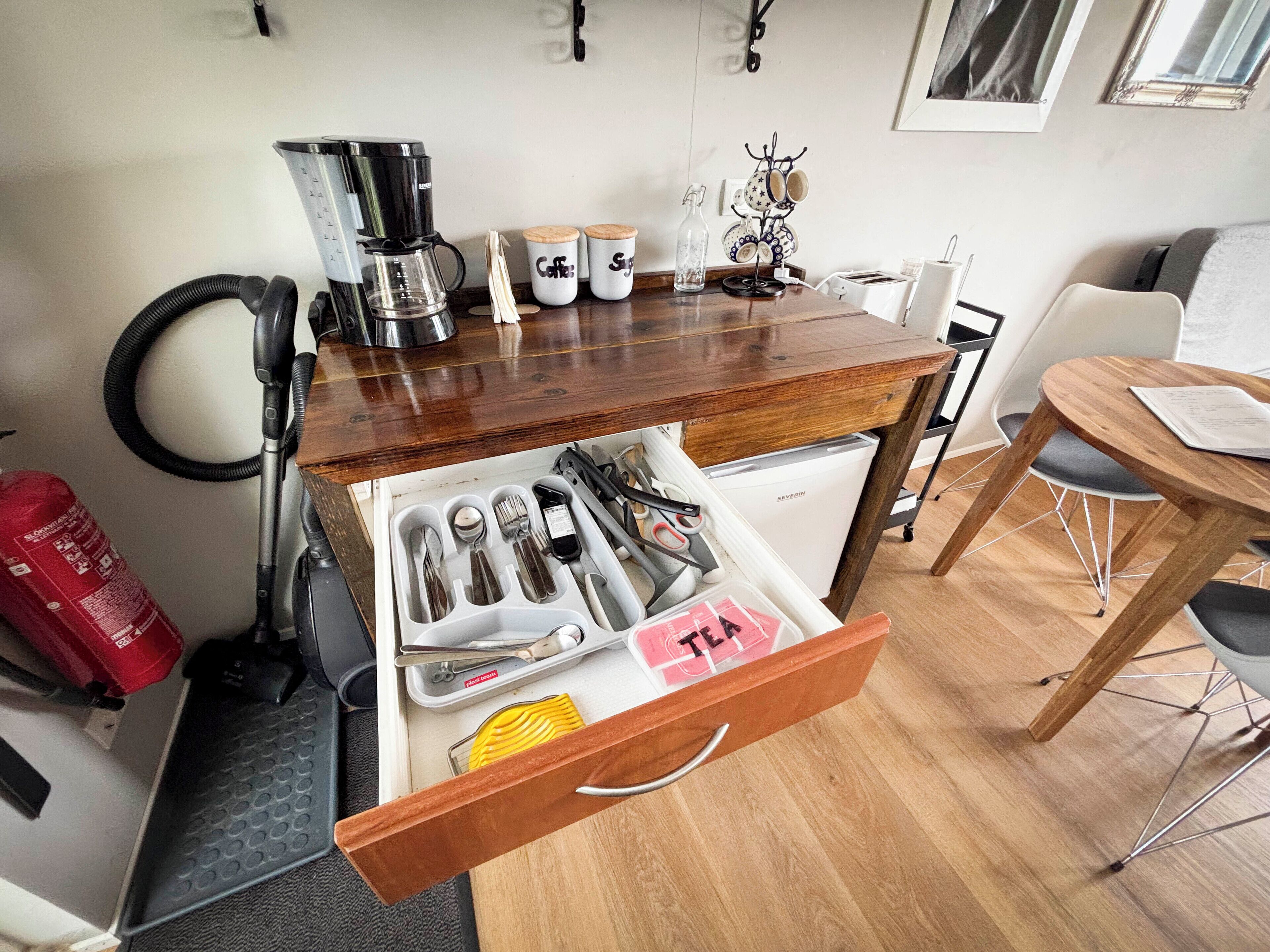 A compact kitchen with a coffee maker, utensils, and a refrigerator.