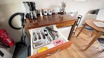 A compact kitchen with a coffee maker, utensils, and a refrigerator.