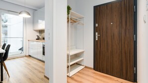 Ett modernt kök med vita skåp, ett trägolv och en matplats med ett bord och stolar.