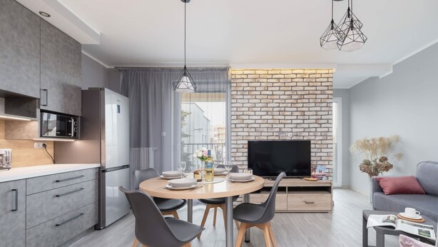 Eine moderne Küche mit Essbereich, einem Flachbildfernseher und einer gemütlichen Sitzecke mit Sofa und Couchtisch.