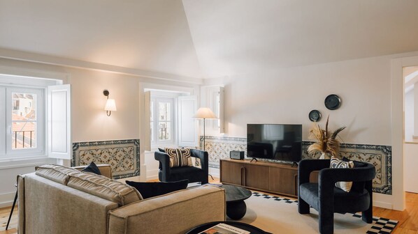 Una sala de estar con un sofá, sillones, una mesa de centro, un televisor y elementos decorativos.