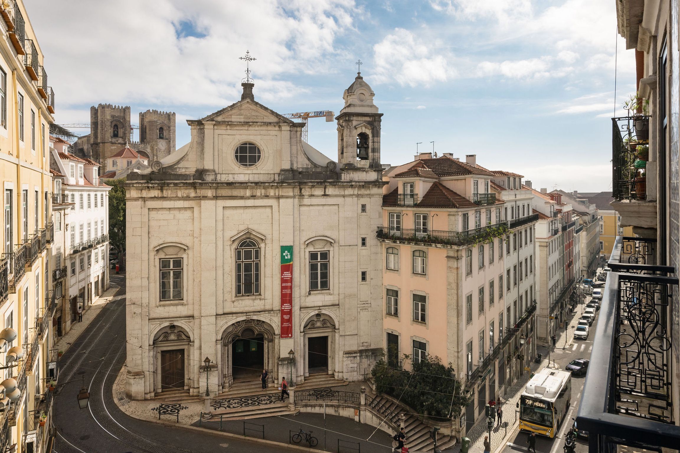 Un edificio histórico con una imponente torre del reloj, una entrada arqueada grande y un estandarte rojo.