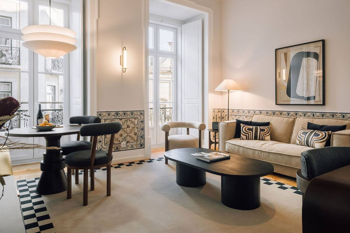 Ein modernes Wohnzimmer mit rundem Tisch, zwei Stühlen, einer Couch, einem Couchtisch und einer Lampe.