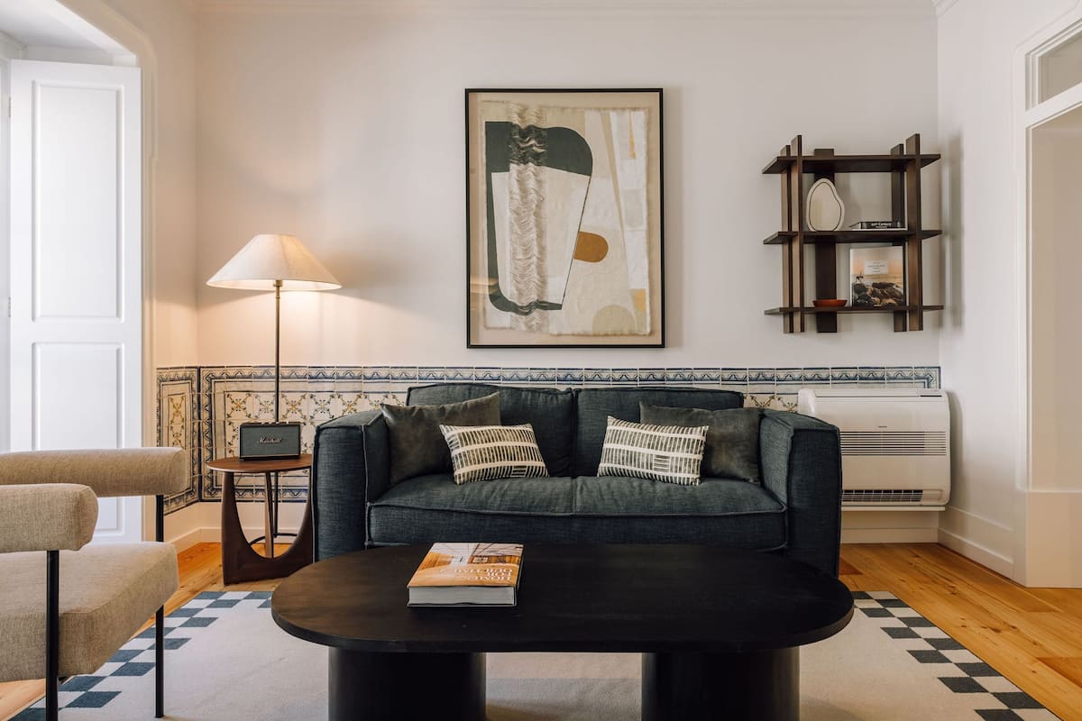 Ein Wohnzimmer mit einer Couch, einem Couchtisch, einer Lampe, einem Bücherregal und einer gefliesten Spritzschutzleiste.