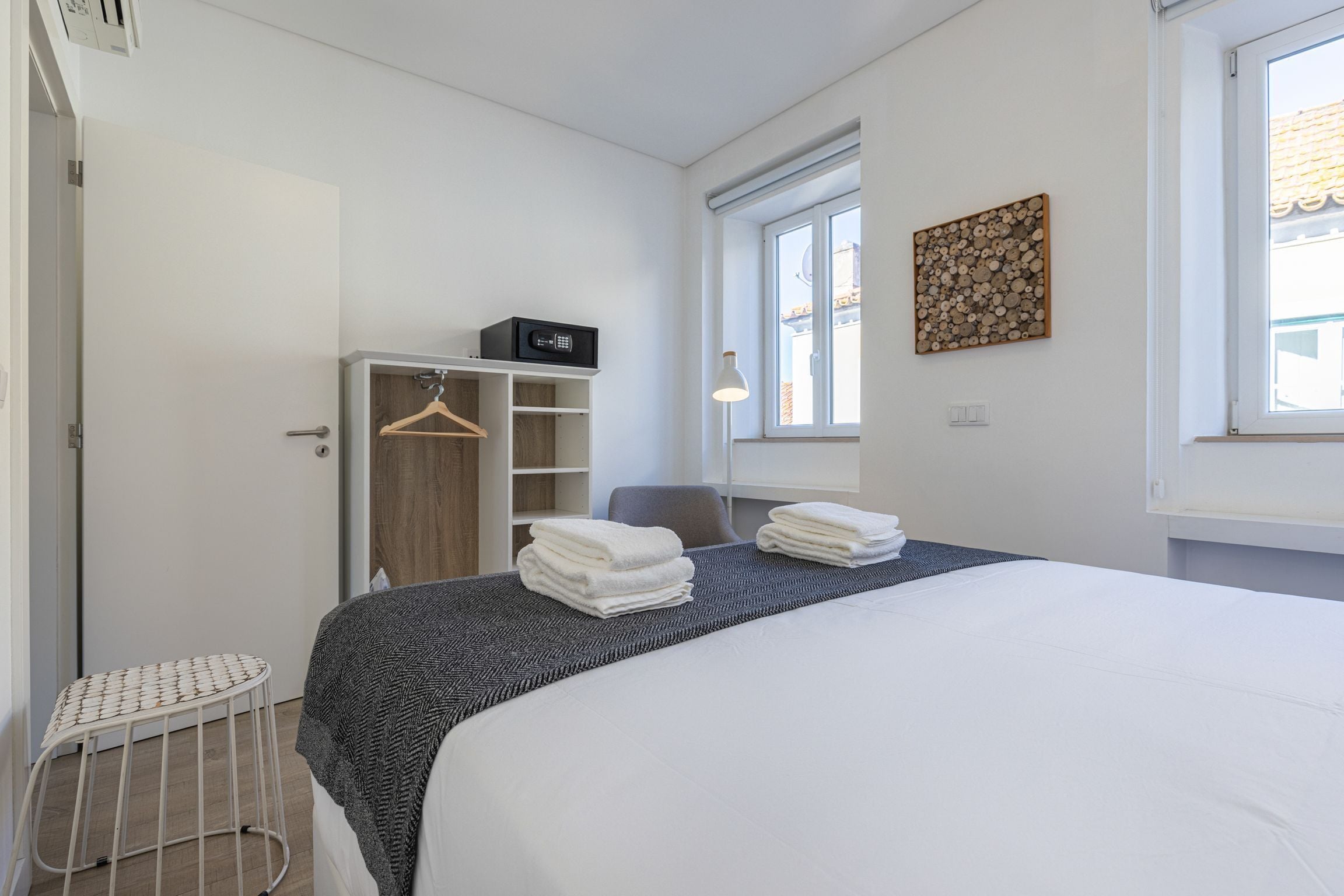 A hotel room with a bed, a wardrobe, a small table, and a window with a view.