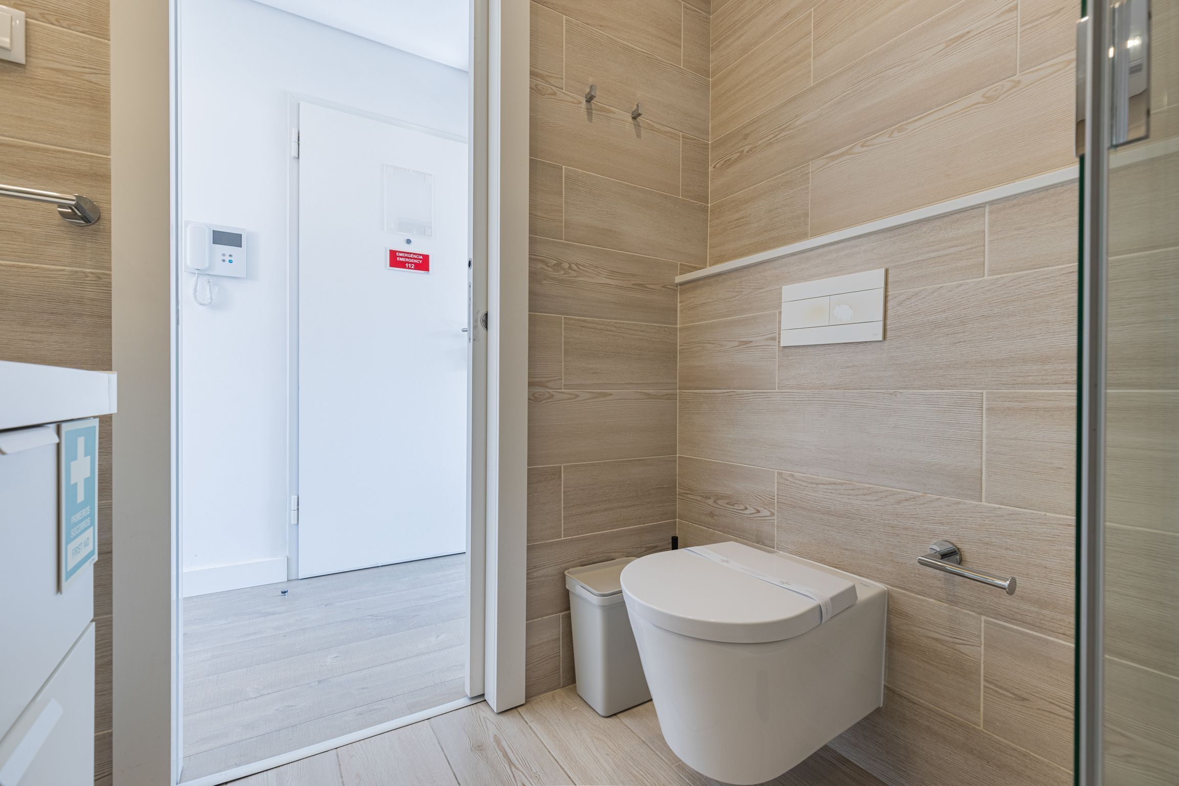 Ein modernes Badezimmer mit Toilette, Mülleimer und Duschbereich.