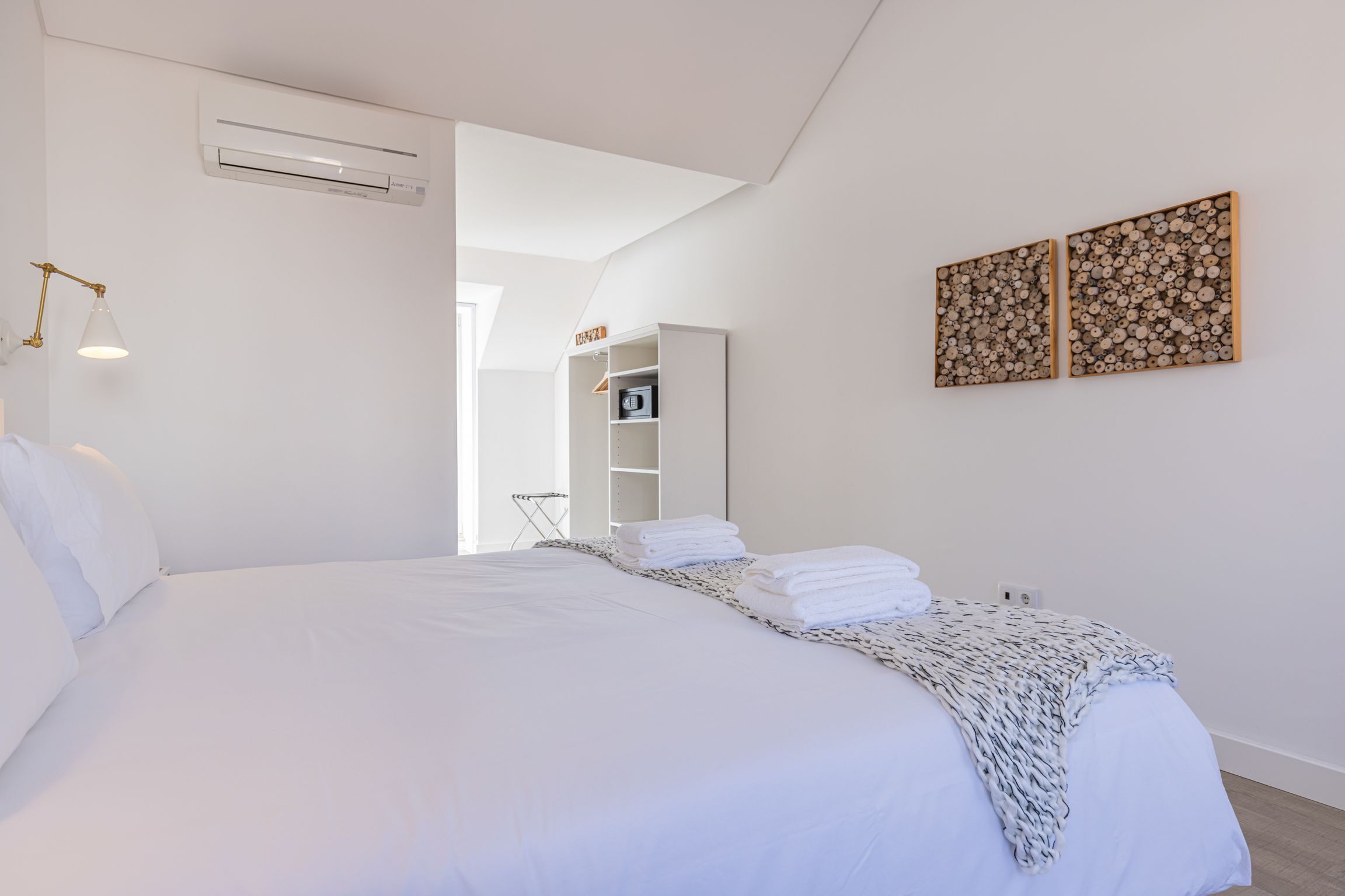 A modern hotel room with a large bed, white walls, and a built-in wardrobe.