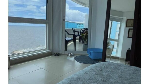 A room with a large window overlooking the sea, a balcony with chairs, and a bed. - CARTAGENA APARTMENT WITH SEA VIEWS (Cartagena de Indias)