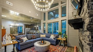 A spacious living room with a large sectional sofa, a round coffee table, and a vibrant patterned rug.