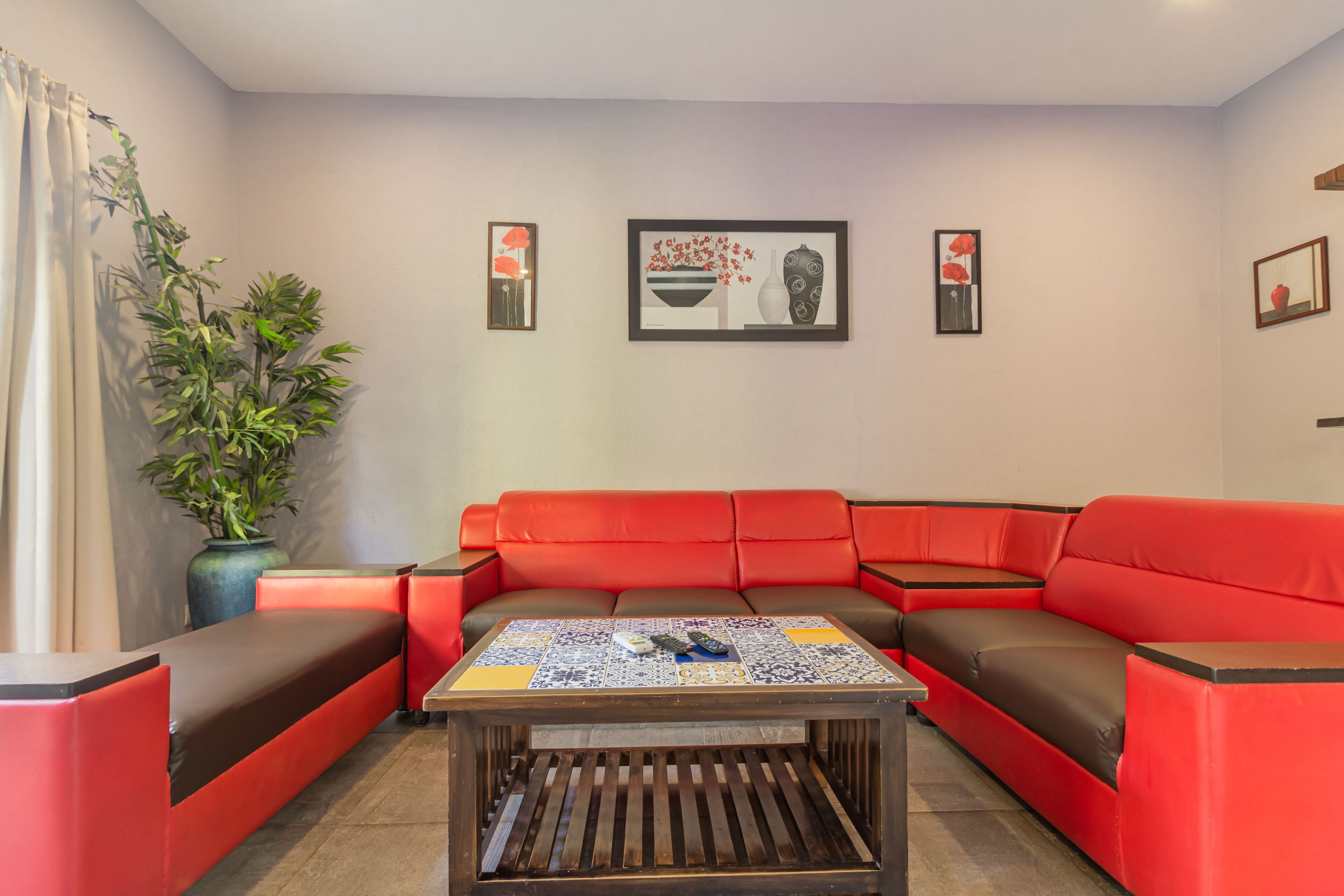 Una sala de estar moderna con un sofá seccional rojo, una mesa de centro con tapa estampada y una planta en maceta.