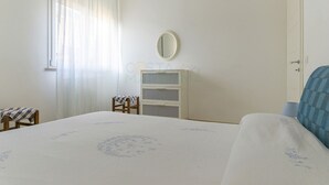 A bedroom with a bed, a chair, a dresser, and a mirror. - PRATORANIERI - GIRASOLE (Follonica)