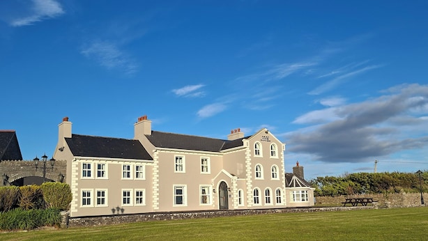 A large, two-story building with a symmetrical facade, multiple chimneys, and a well-maintained lawn in front. - Enjoy the breathtaking view which you Relax at the Aran View Lodge (Doolin)