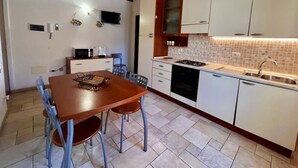 Una cucina compatta con pensili bianchi, piastrelle a mosaico, un tavolo con sedie e un piano cottura integrato.