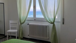 Une pièce avec une fenêtre, un radiateur et une chaise blanche.