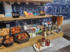 Un buffet de petit-déjeuner proposant des croissants, des viennoiseries et diverses confitures.