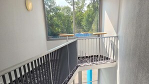 A staircase with metal railings and a window overlooking greenery. - Kyriad Direct Lyon Nord - Dardilly (Dardilly)