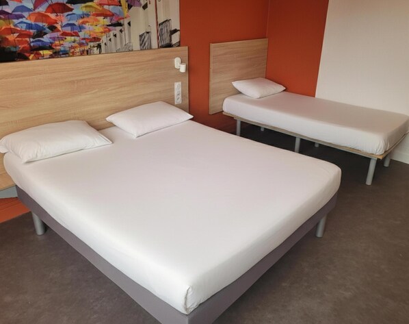 A hotel room with a large bed, a smaller bed, and a headboard with a mirror.