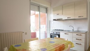 Een kleine keuken met een tafel bedekt met een tafelkleed met bloemenprint, een spoelbak en kastjes.