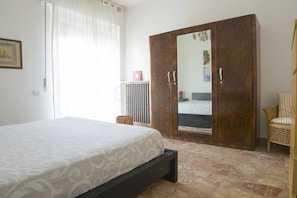 Ein Schlafzimmer mit Bett, Kleiderschrank, Stuhl und Heizkörper.