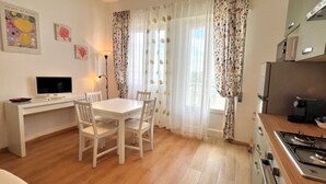 A small kitchen with a dining table and chairs, a TV, and a stove. - SPIAGGIA DI LEVANTE - ELBA (Follonica)