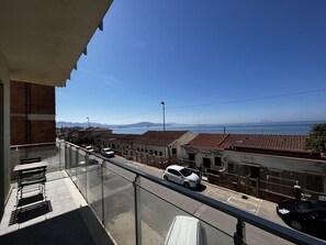 A balcony with a view of a coastal street, buildings, and a distant ship. - SPIAGGIA DI LEVANTE - PALMAIOLA (Follonica)