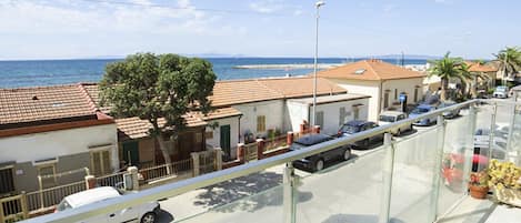 Une zone résidentielle côtière avec des maisons, un ciel dégagé et la mer en arrière-plan.