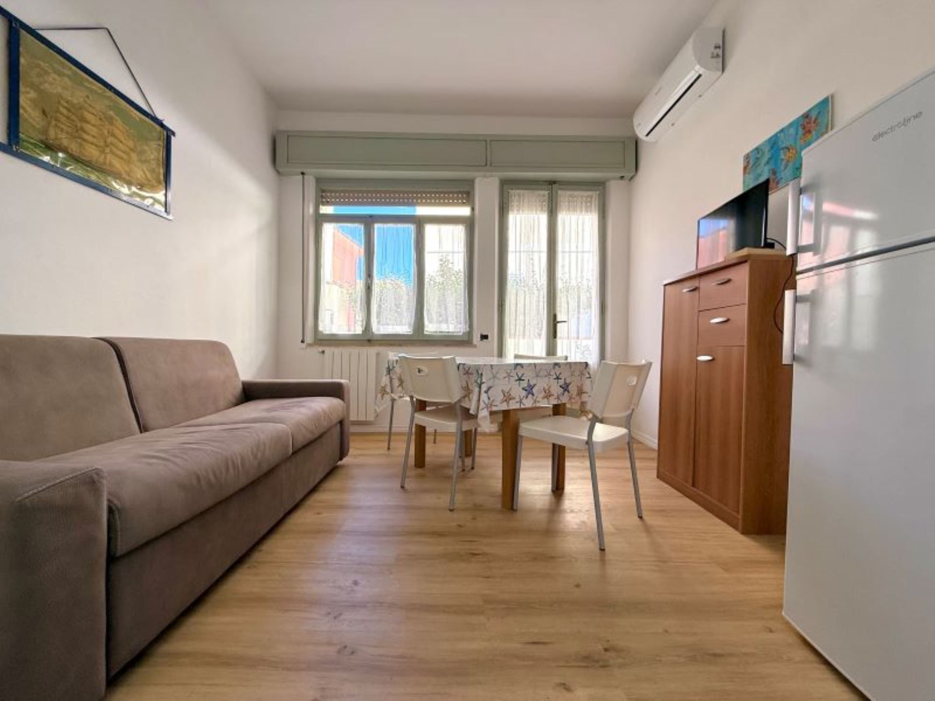 Un espace de vie compact comprenant un canapé, une table à manger, des chaises et un réfrigérateur.