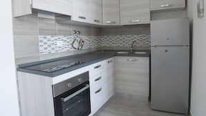 Una cocina moderna con armarios de madera clara, un refrigerador de acero inoxidable y un salpicadero de azulejos.
