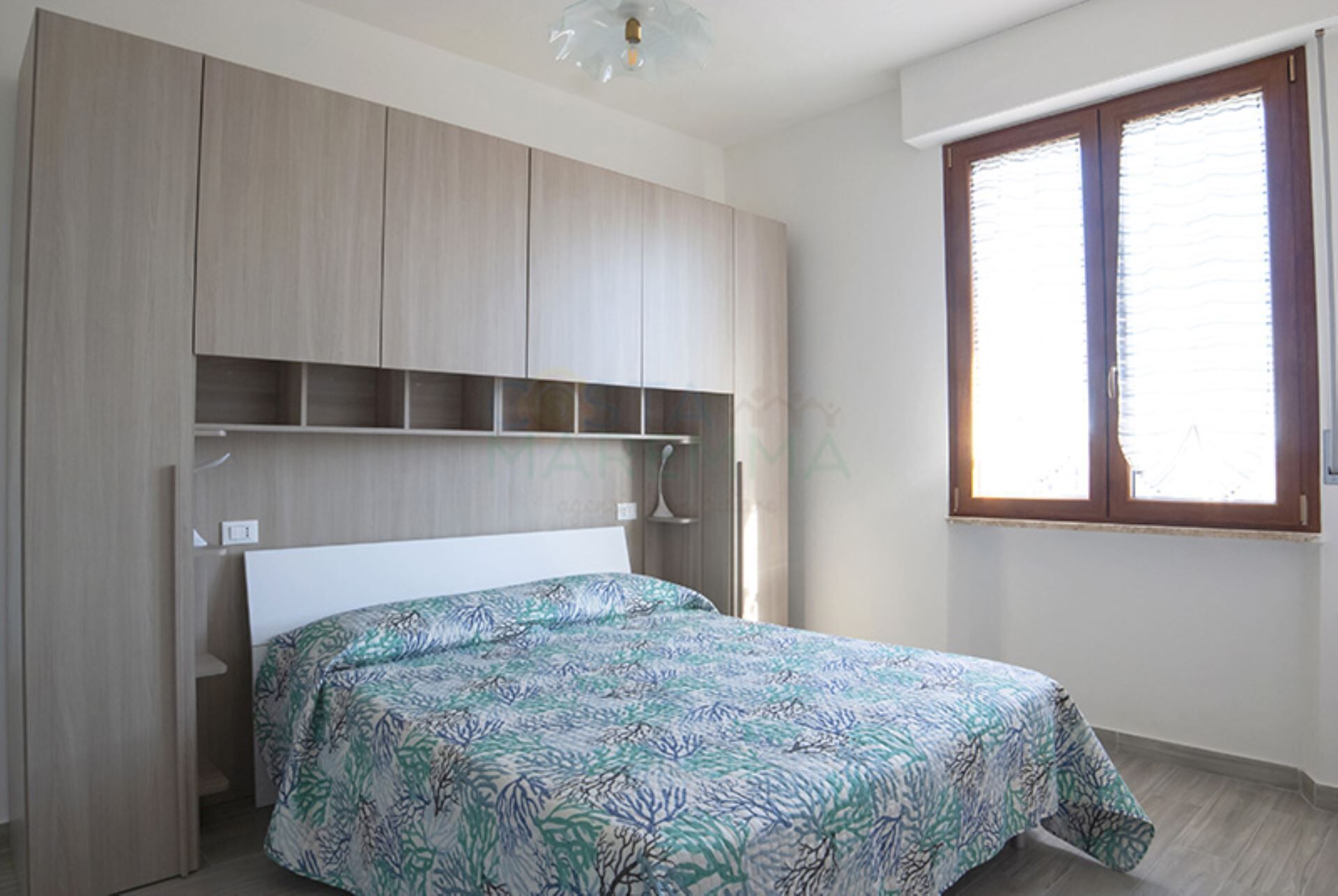 A bedroom with a bed, a wardrobe, and a window.