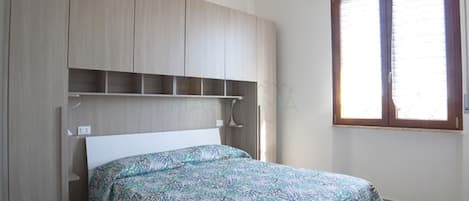 A bedroom with a bed, a wardrobe, and a window.