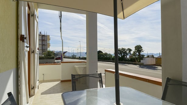 A balcony with a table and chairs, overlooking a road and distant mountains. - Alba apartment in Follonica (Follonica)