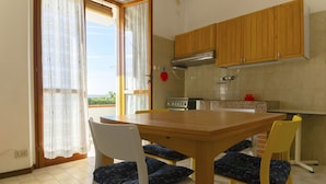 A kitchen with wooden cabinets, a stove, and a dining table with chairs. - Alba apartment in Follonica (Follonica)