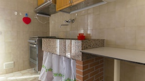 A kitchen with a stove, oven, and a red heart-shaped object on the wall. - Alba apartment in Follonica (Follonica)