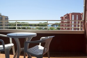 Een balkon met een tafel en stoelen, met uitzicht op een waterpartij en gebouwen.