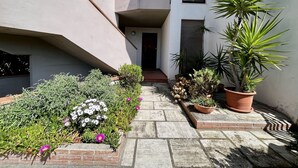 A narrow outdoor corridor with a stone floor, surrounded by various potted plants and flowers. - Pini apartment in Follonica (Follonica)