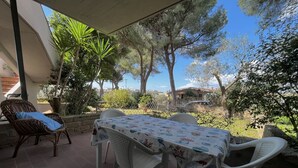 An outdoor patio with a table and chairs, surrounded by greenery and a view of the sea. - Pini apartment in Follonica (Follonica)