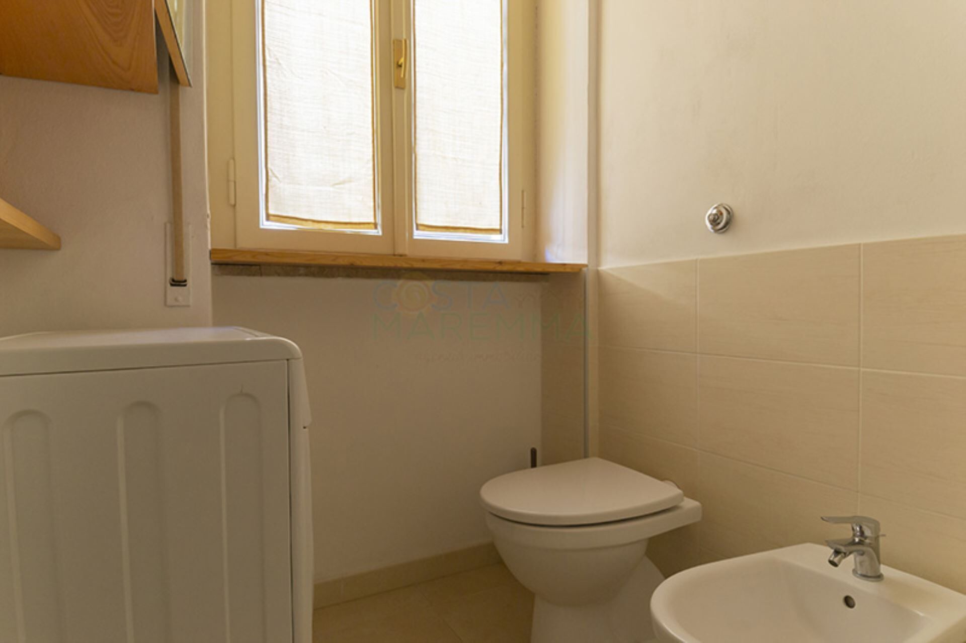 A bathroom with a toilet, a sink, and a window.