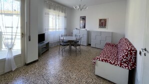A compact living space with a dining area, kitchenette, and a sofa. - Papavero apartment in Follonica (Follonica)