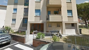 A multi-story residential building with balconies, a visible antenna, and a gated entrance. - Papavero apartment in Follonica (Follonica)