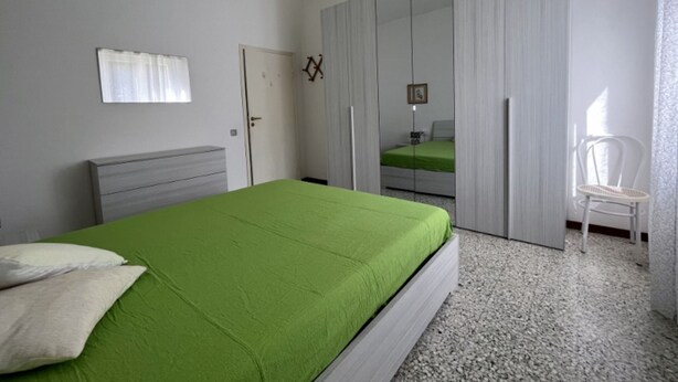 A bedroom with a bed, a chair, a wardrobe, and a door. - Papavero apartment in Follonica (Follonica)