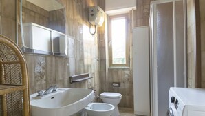 A bathroom with a large sink, a bidet, a toilet, and a washing machine. - Salvia apartment in Follonica (Follonica)