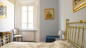 Ein Schlafzimmer mit Bett, Stuhl, Fenster und Heizkörper.
