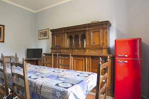 A bedroom with a bed, wooden headboard, a red refrigerator, and a television on a stand.