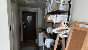 Une chambre d’hôtel compacte comprenant un coin cuisine, un petit espace salon et une porte donnant sur une autre pièce.