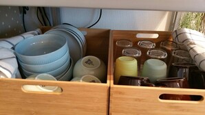 Un tiroir de cuisine contenant des assiettes, des bols et des bocaux empilés.